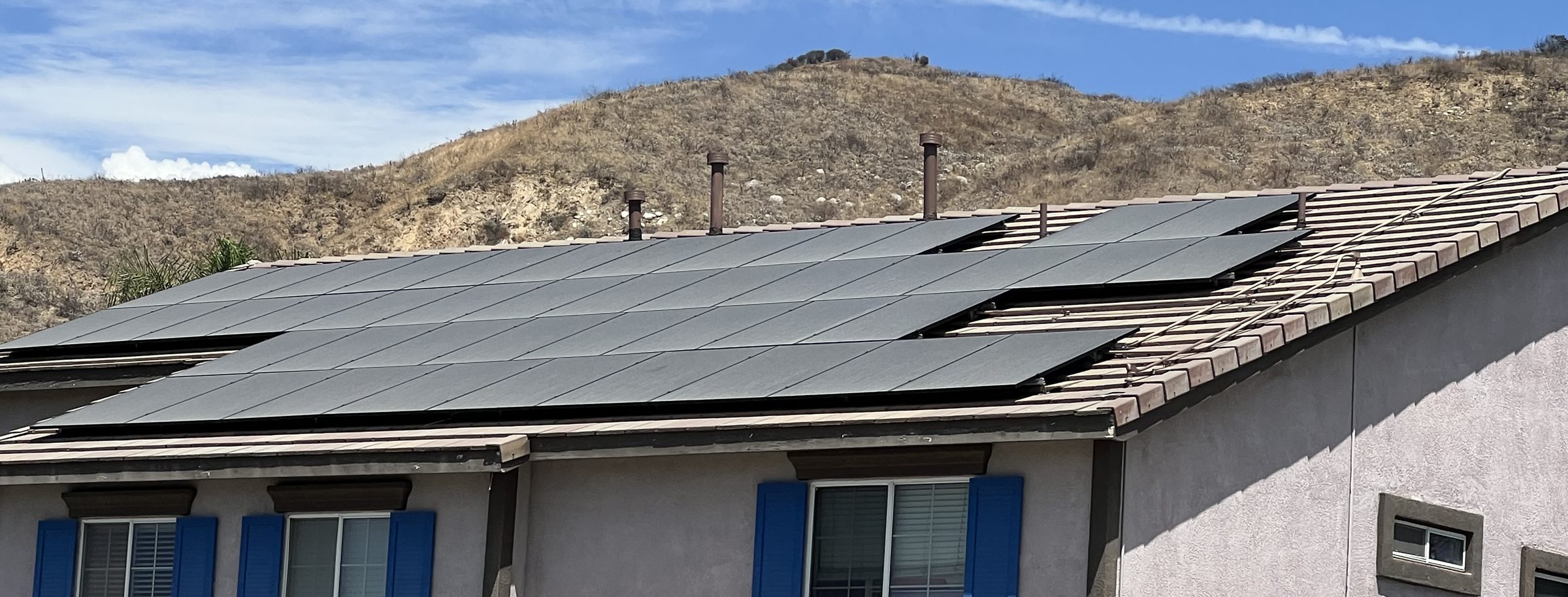 Rooftop solar array on a tile-roof home in the Inland Empire, with dry foothills behind it.