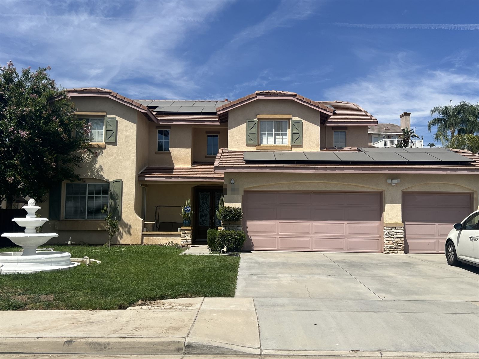 Two-story stucco home with a tile roof and a rooftop solar array above the garage.